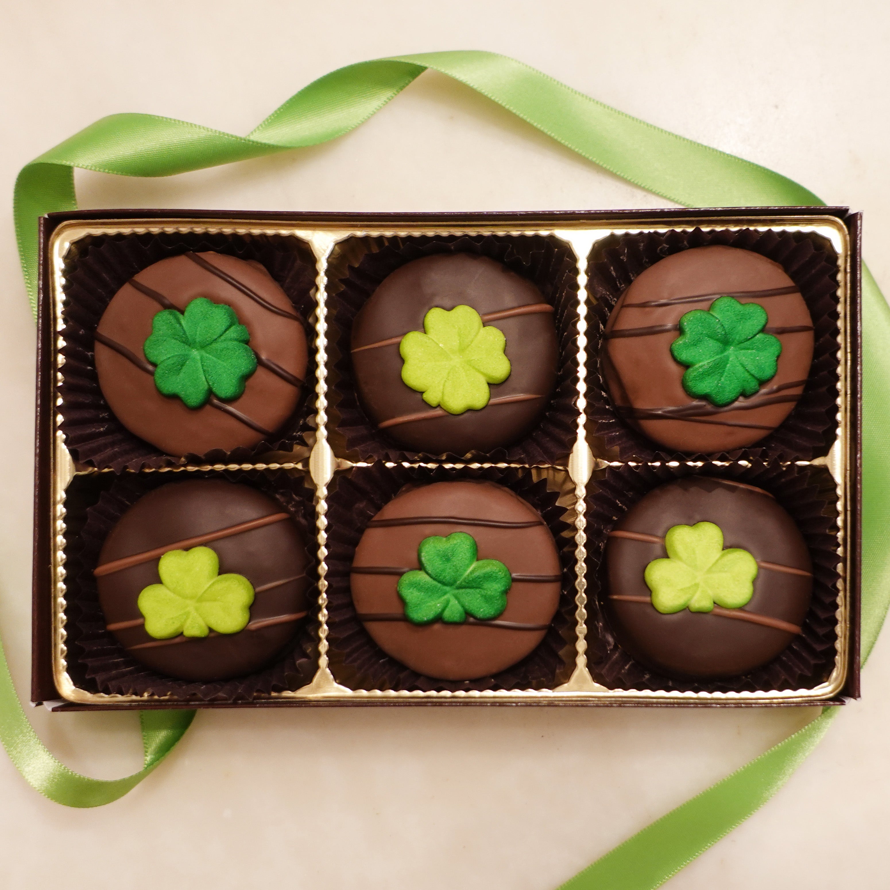 Assorted Milk and Dark Chocolate covered oreos with shamrock clover sugar decorations in two different shades of green and 3 or 4 leaves 