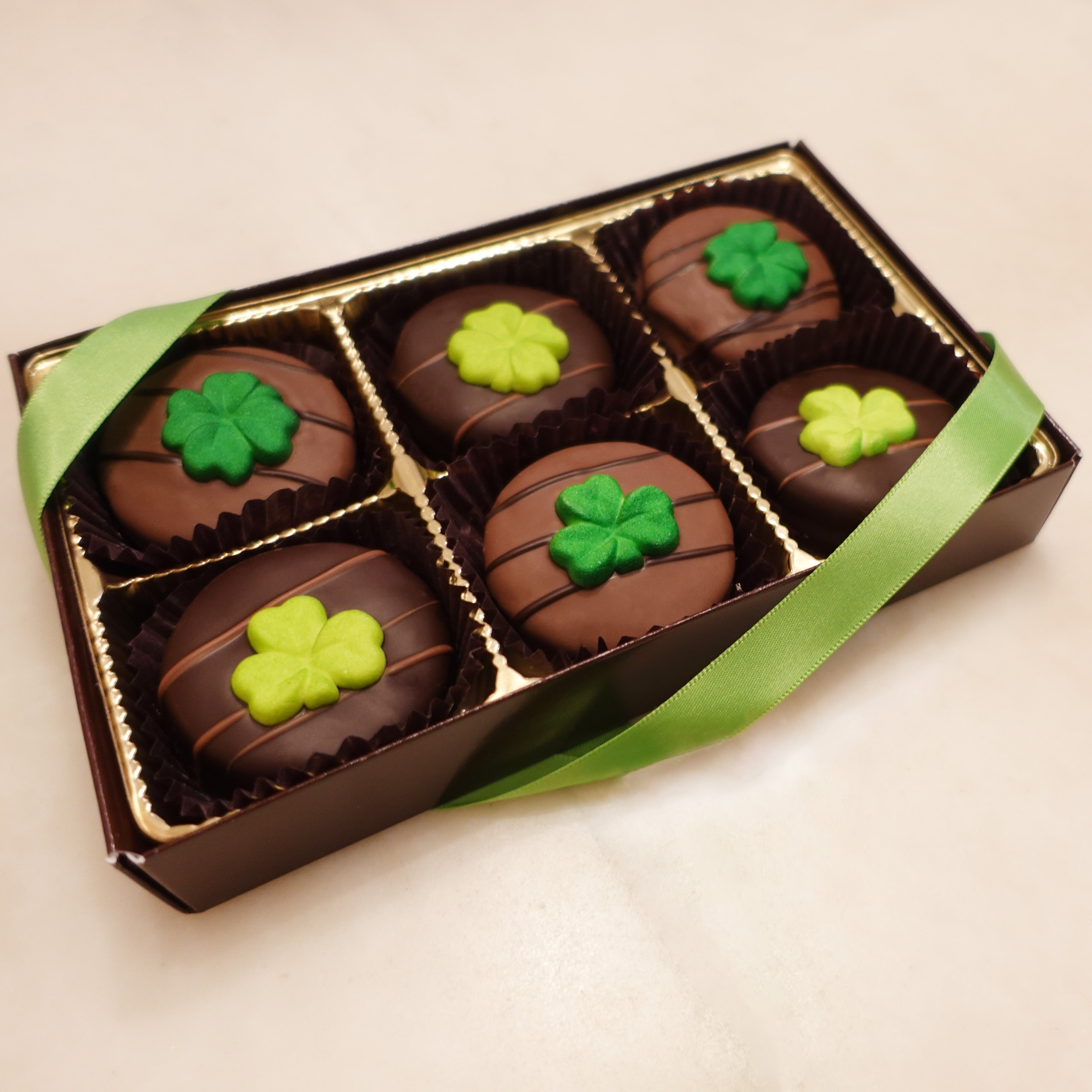 Assorted Milk and Dark Chocolate covered oreos with shamrock clover sugar decorations in two different shades of green and 3 or 4 leaves 