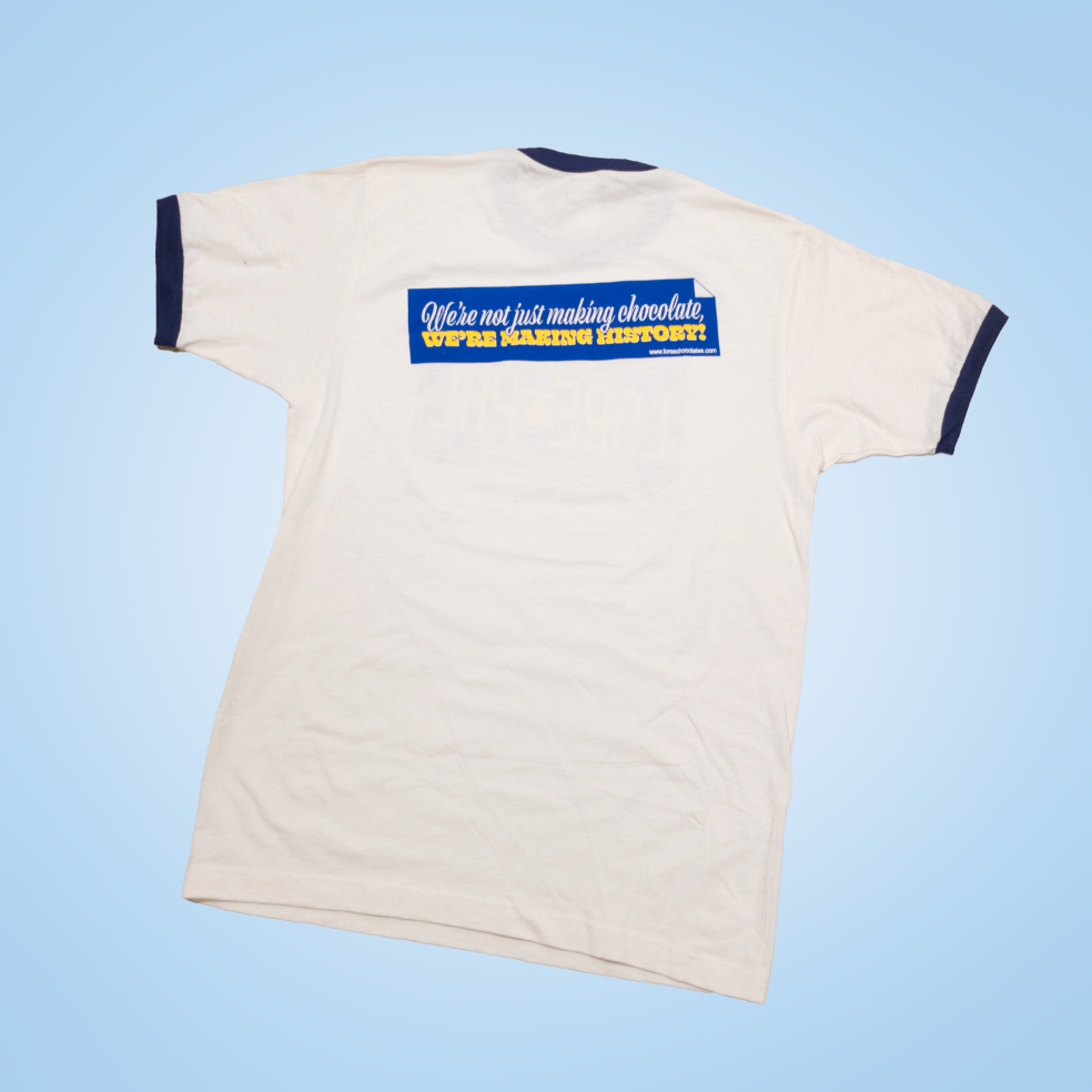 loreschocolates vintage white t-shirt with dark blue ringer sleeves and neck - back with a bumper sticker design reading "We're not just making chocolate, we're making history!"