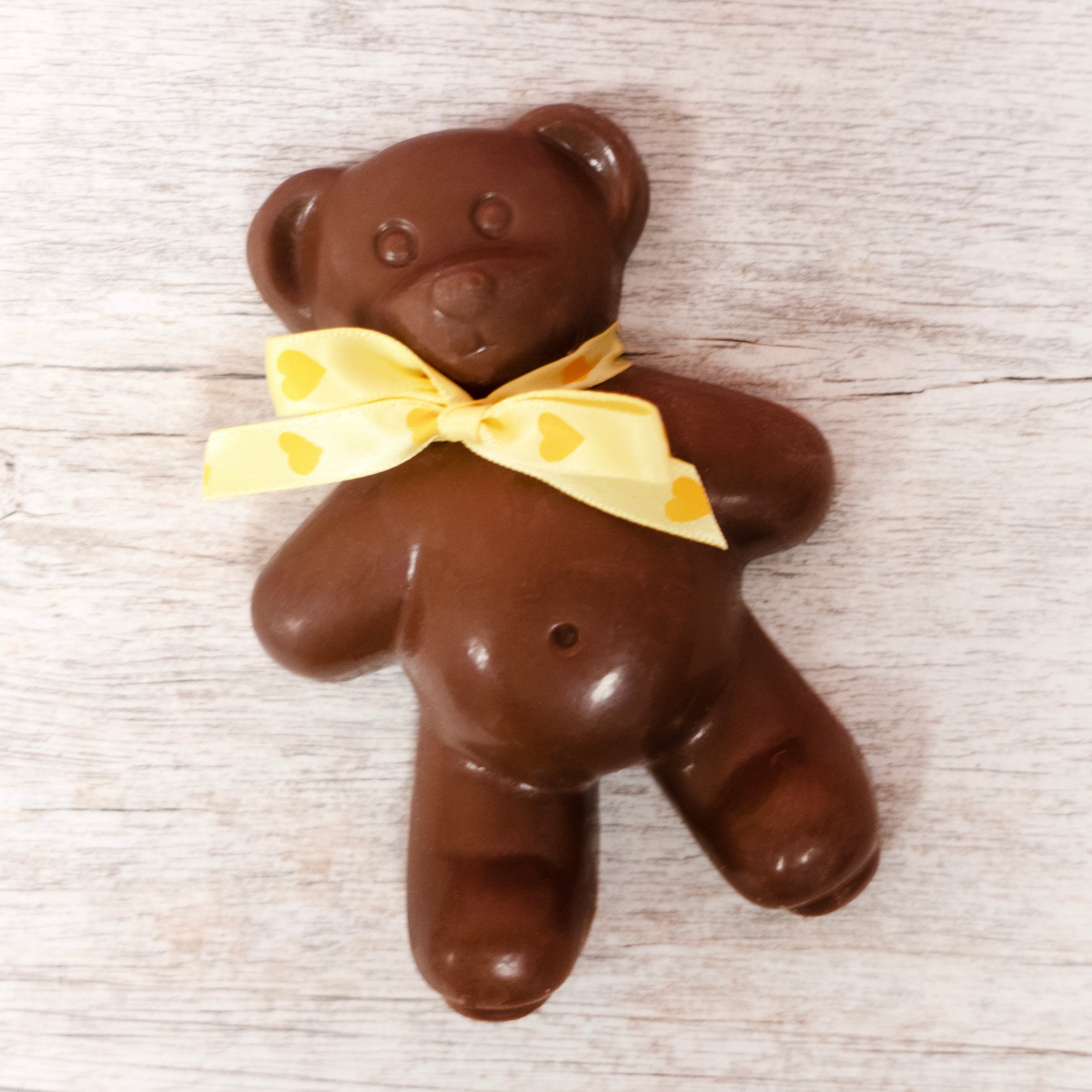 solid Lore's Milk Chocolate Teddy bear with a yellow ribbon bow with hearts around it's neck for Valentine's Day