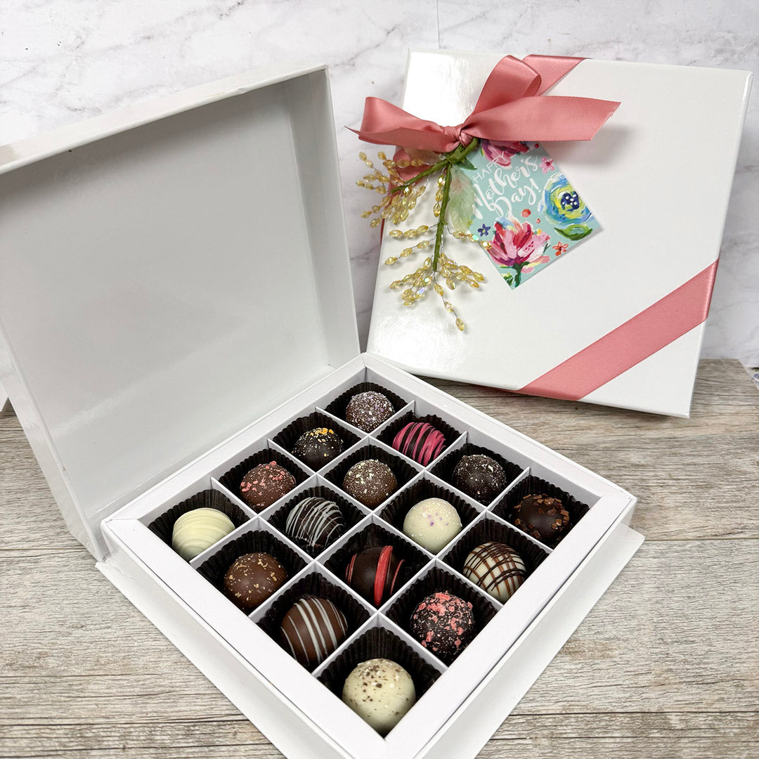 Box of chocolate truffles with a floral card on a wooden surface