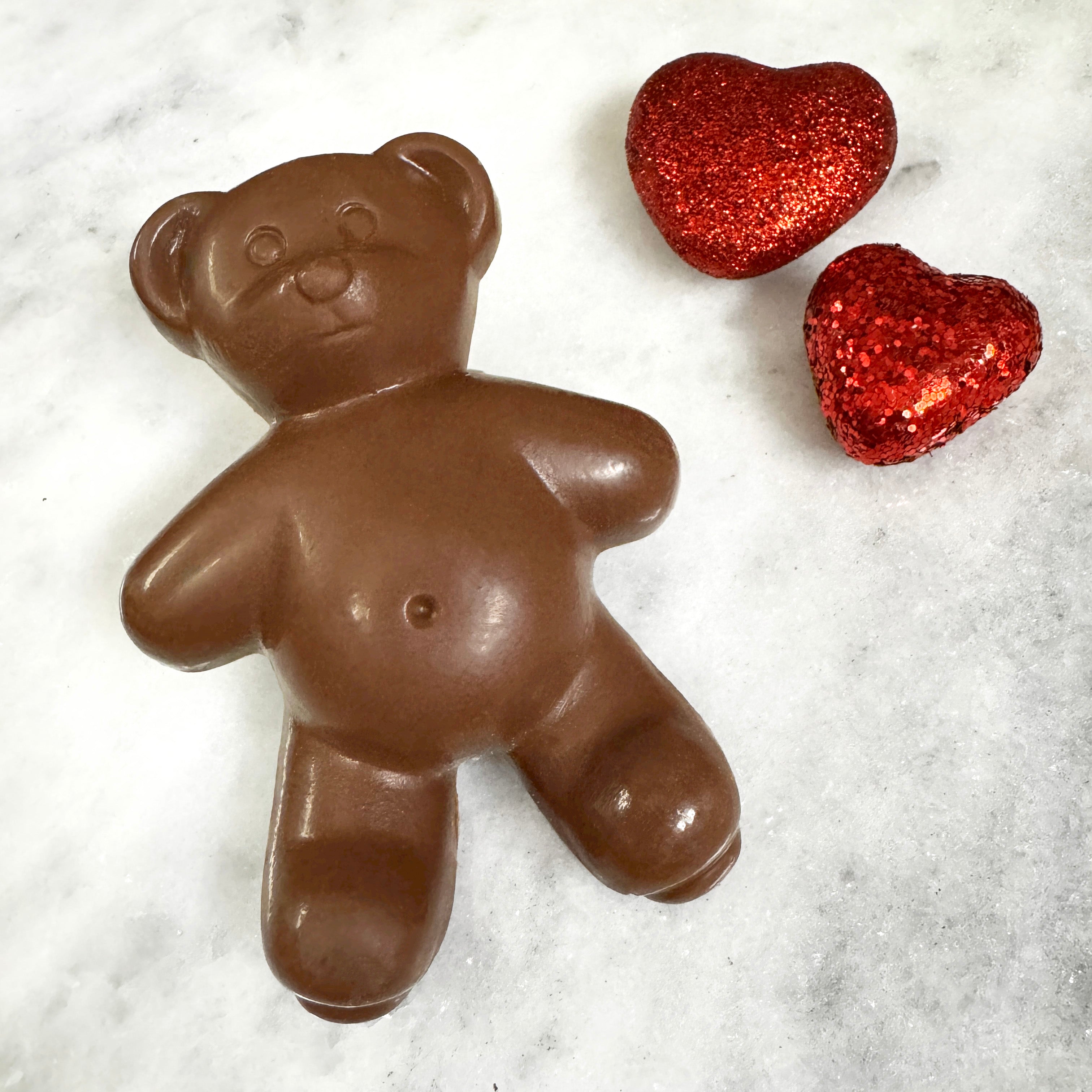 solid milk chocolate teddy bear for valentine's day with sparkly red hearts in background of photo