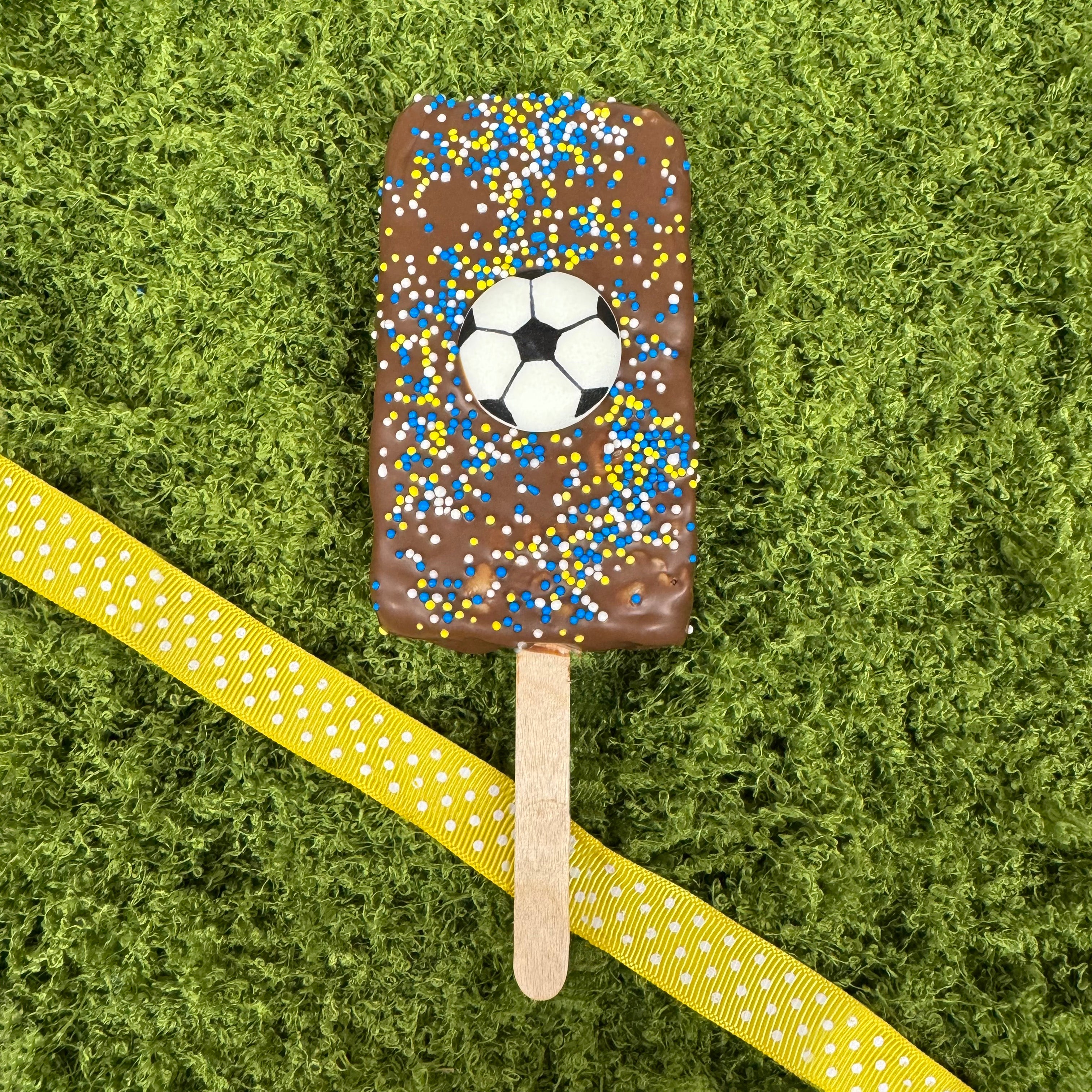 Chocolate-covered rice krispie treat with a soccer ball design on a green grass background - for FIFA 2026 in Philly