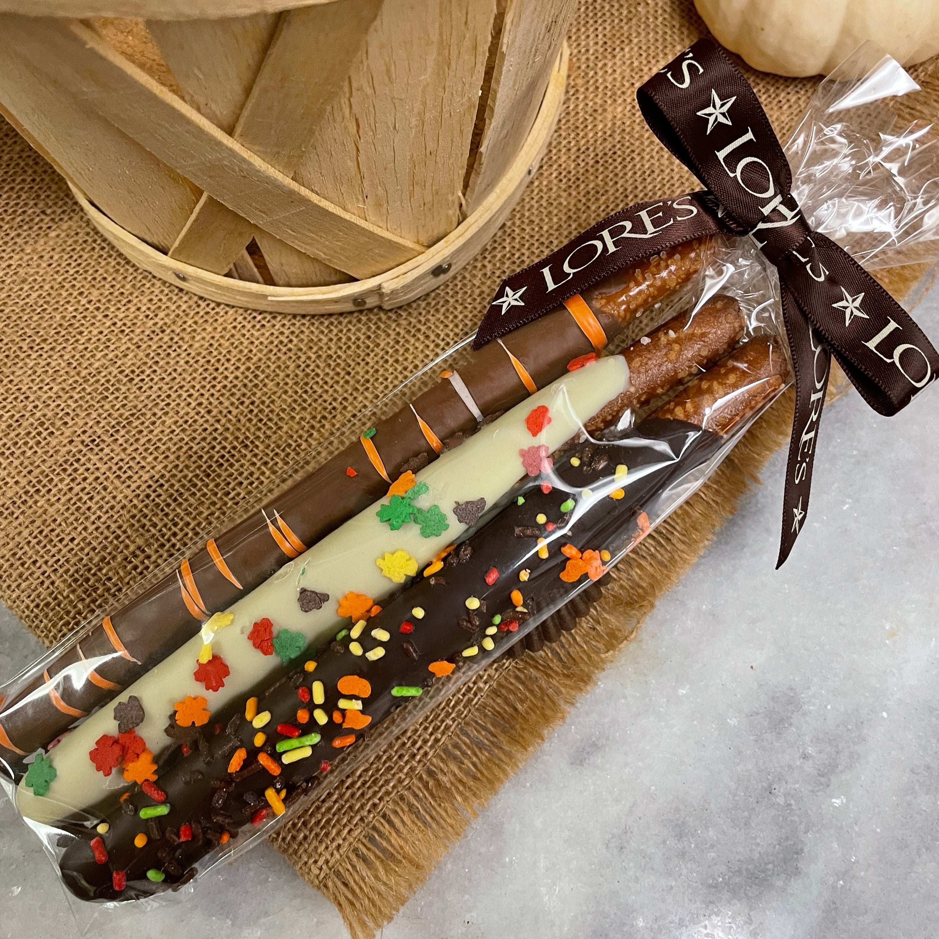 Three pretzel rods dipped in chocolate - one milk, one dark, and one white with fall sprinkles