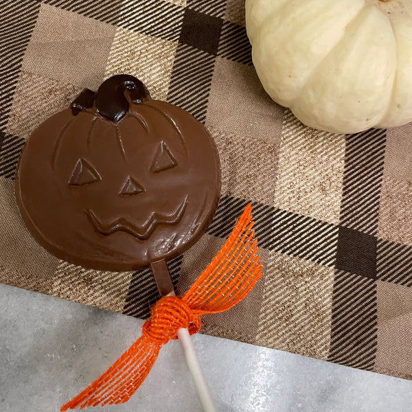 Lore's chocolate pumpkin face pop - milk chocolate with a dark chocolate stem