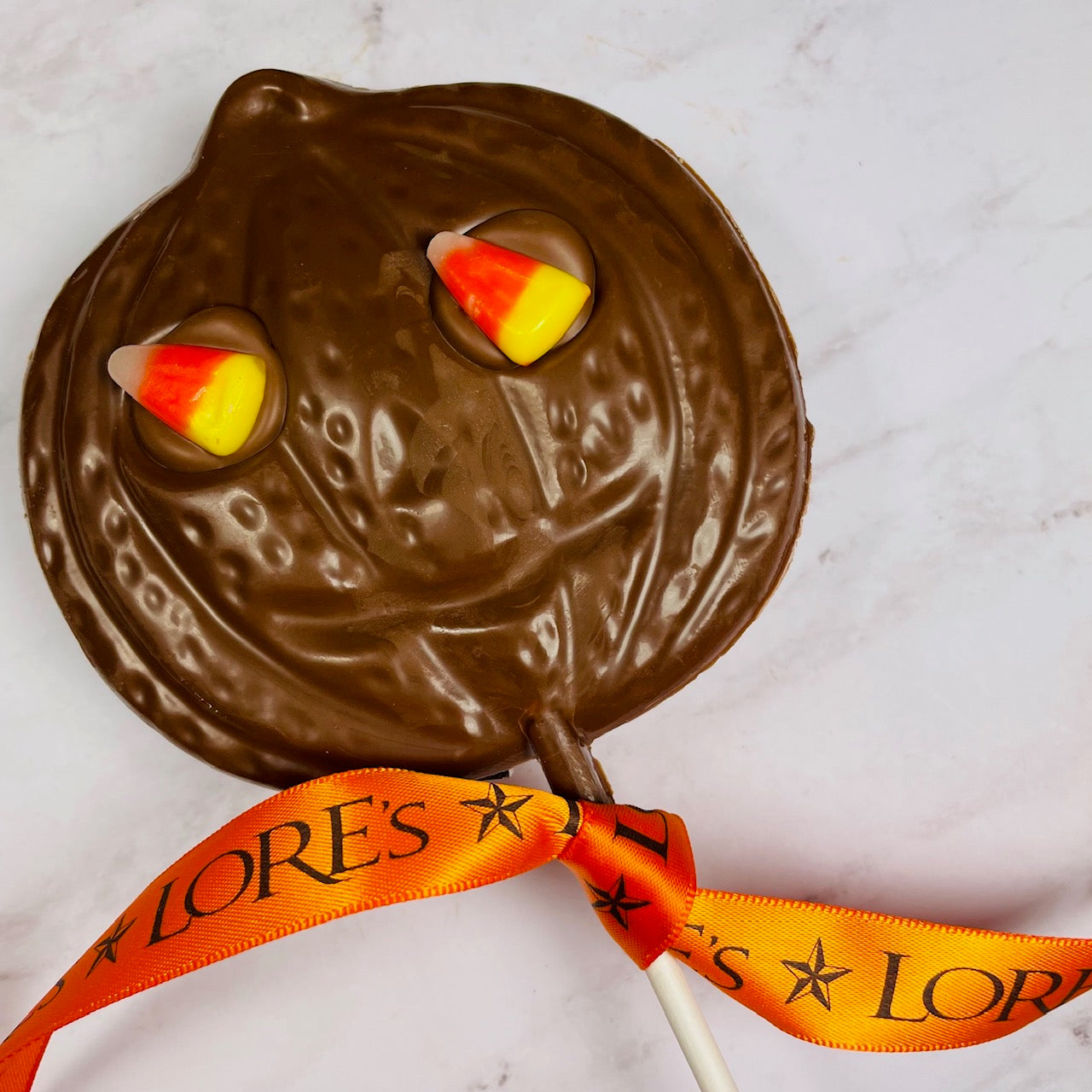 Milk Chocolate jack-o-lantern pumpkin faced lollipop with candy corn eyes.