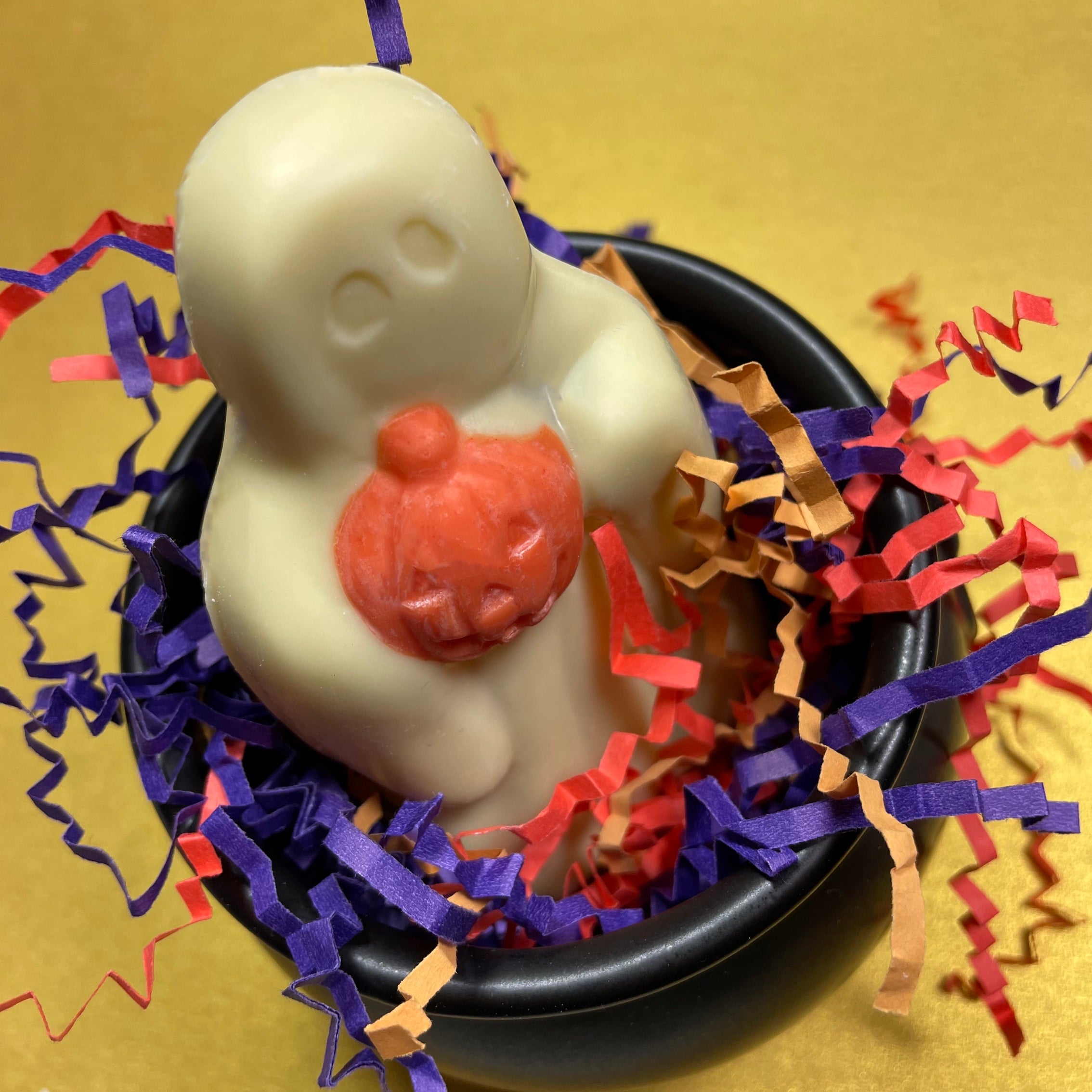 White chocolate ghost holding an orange jack-o-lantern pumpkin
