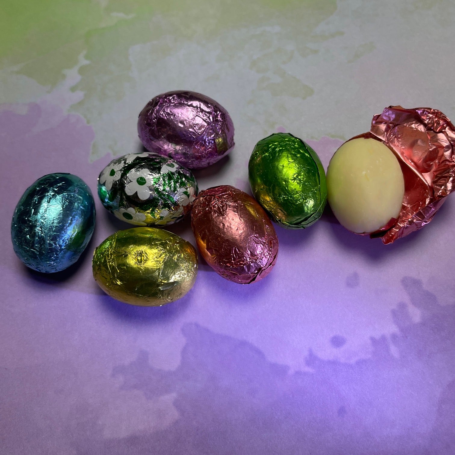 solid bite-sized white chocolate eggs - individually wrapped - spring foil: blue, yellow, silver with white flowers, purple, and pink