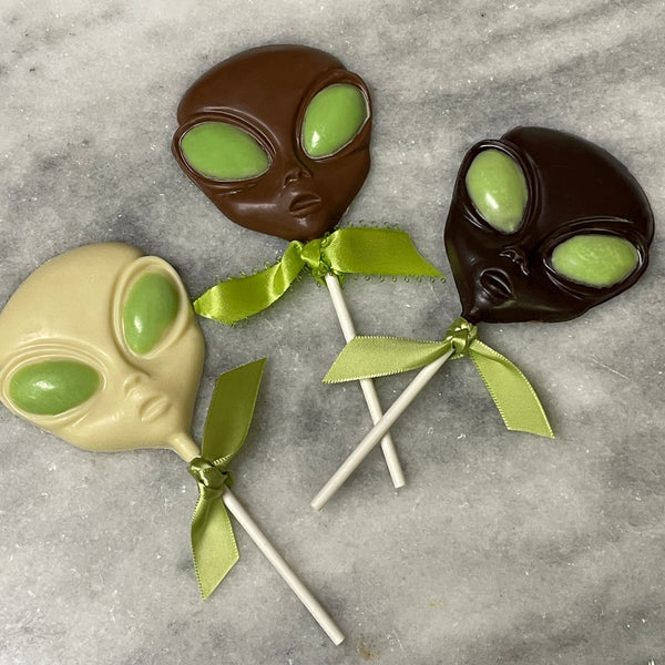 Chocolate alien lollipops in white, milk, and dark chocolate - with light green eyes made of white chocolate.