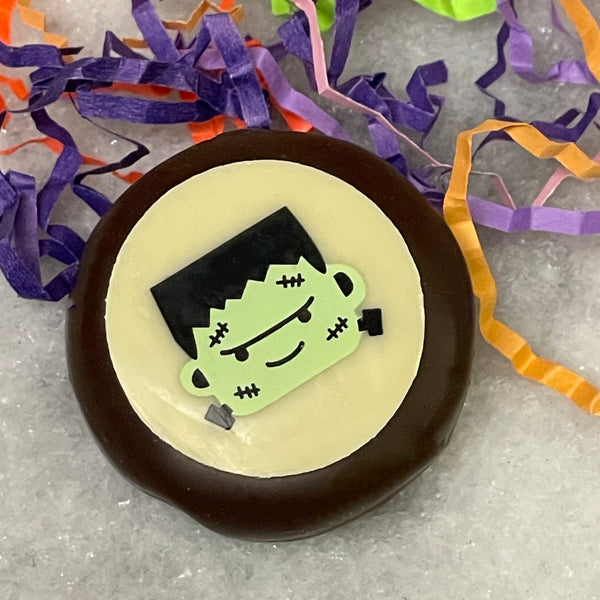 Oreo covered in dark chocolate with a white chocolate accent showing a cute Frankenstein's monster