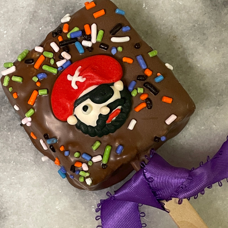 Milk Chocolate covered rice crispy treat on a stick with a pirate design and Halloween colored sprinkles.