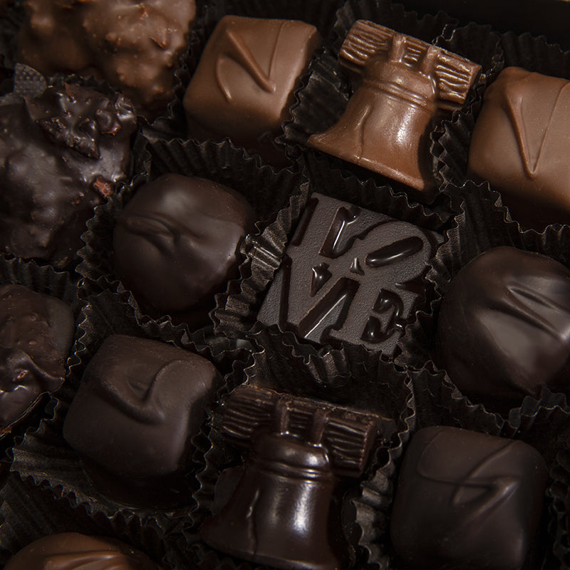 Close up of locally made Philadelphia chocolates shaped like the LOVE sculpture and the liberty bell along with other assorted milk and dark chocolates.